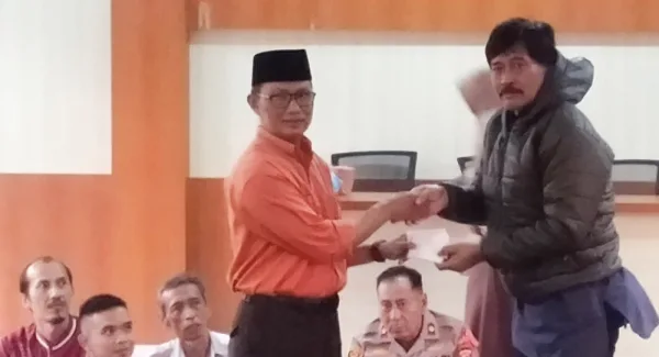 Camat Tanjungsari, Agus Beni Triadhie menyerahkan secara simbolis kartu keanggotaan BPJS untuk Marbot di desa dalam Buka Bersama pada Jumat (13/3/2026)