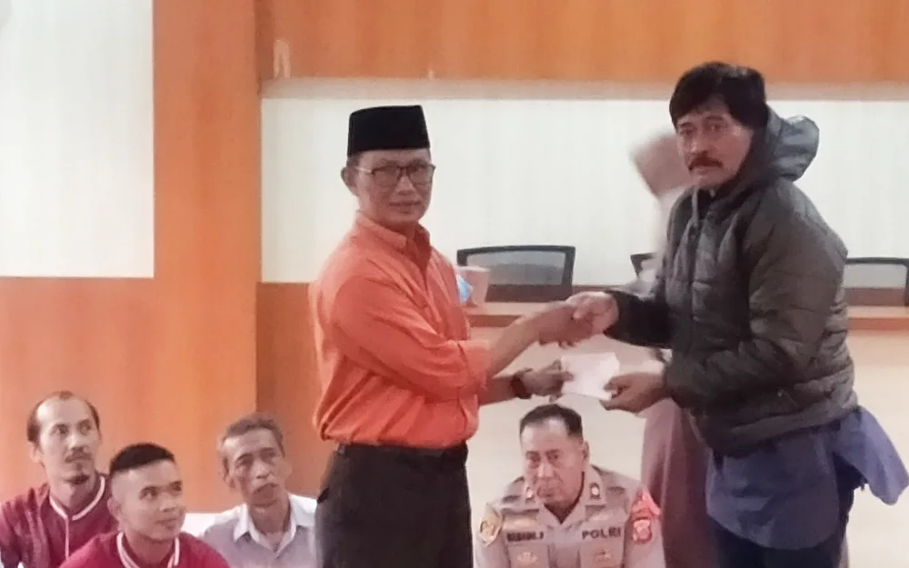 Camat Tanjungsari, Agus Beni Triadhie menyerahkan secara simbolis kartu keanggotaan BPJS untuk Marbot di desa dalam Buka Bersama pada Jumat (13/3/2026)