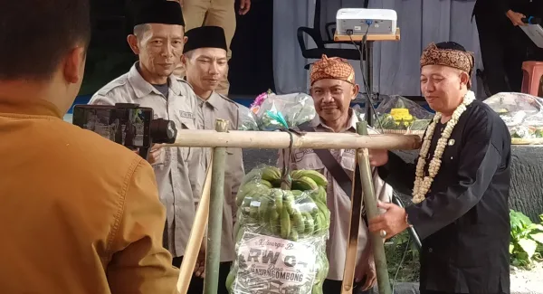 Penyerahan hasil bumi secara simbolis dari masyarakat kepada Kepala Desa Haurngombong, Dadang di acara Milangkala ke-44 pada Senin (22/6/2026)