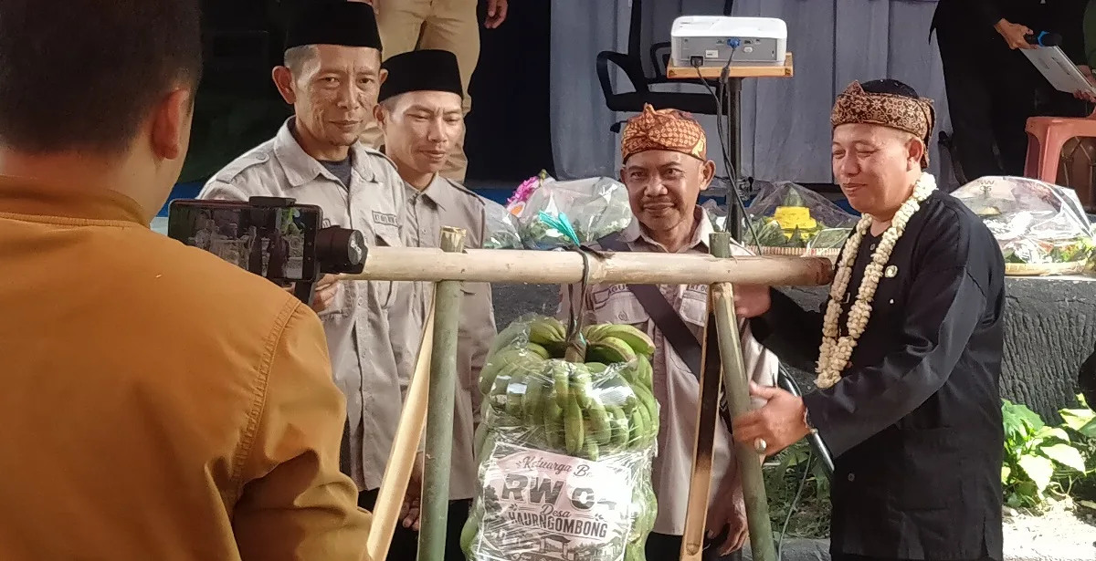 Penyerahan hasil bumi secara simbolis dari masyarakat kepada Kepala Desa Haurngombong, Dadang di acara Milangkala ke-44 pada Senin (22/6/2026)